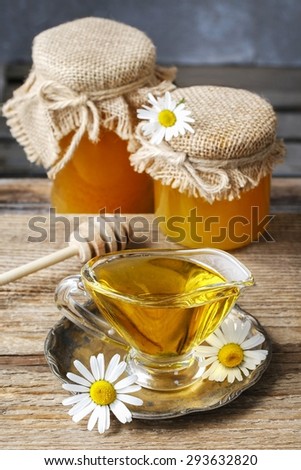 Jars and glass jug of honey on wooden table