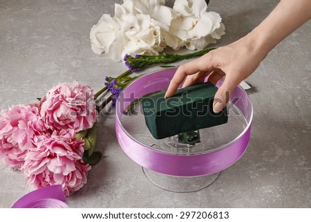 Florist at work: woman arranging floral decorations with pink peonies and white hortensia flowers (hydrangea)