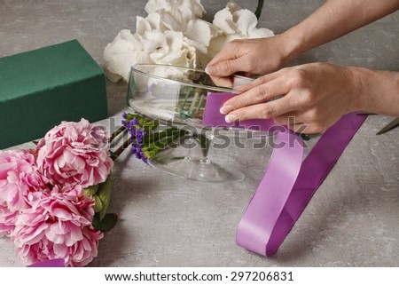 Florist at work: woman arranging floral decorations with pink peonies and white hortensia flowers (hydrangea)