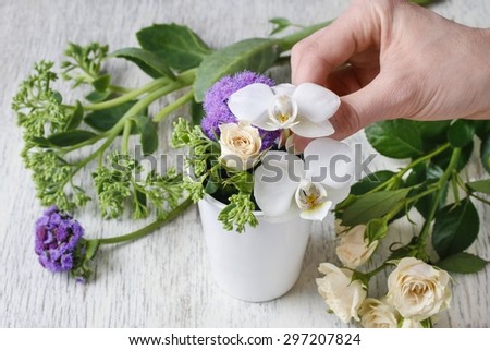 Florist at work: woman arranging floral decorations with roses and white orchids