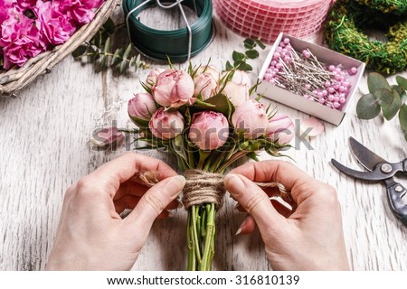 Florist at work: woman making bouquet of pink roses.