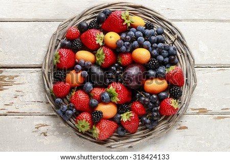 Basket of fruits: strawberries, blueberries, blackberries, grapes and kumquats.
