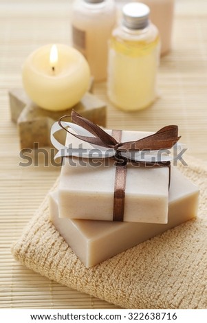 Bars of handmade soap, scented candle and bottles with liquid soap.