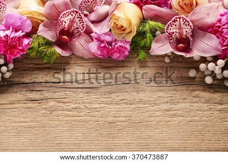 Floral arrangement with orchids, roses and carnations on wooden background, copy space.
