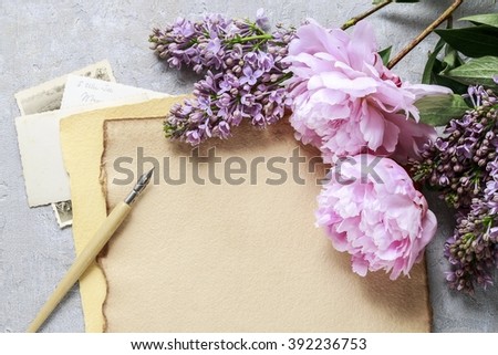 Handwritten letters lilacs and pink peonies on grey background, copy space
