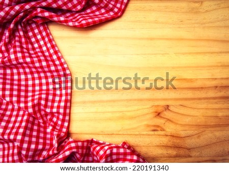 Empty wooden table covered with red checked tablecloth.