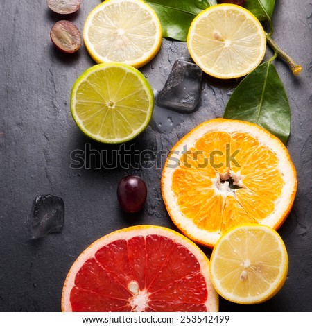 Set of sliced citrus fruits lemon, lime, orange, grapefruit with ice over stone black background. Top view.
