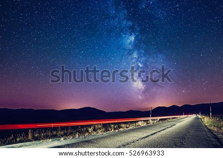 Night sky with milky way and stars. Night road illuminated by car. Light trails Colorful Galaxy