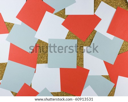 A bulletin cork board background with messy square pieces of white, blue and red posting paper.