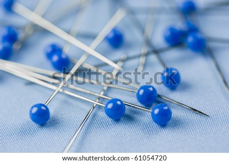 Detail of blue sewing pins on blue textile background.