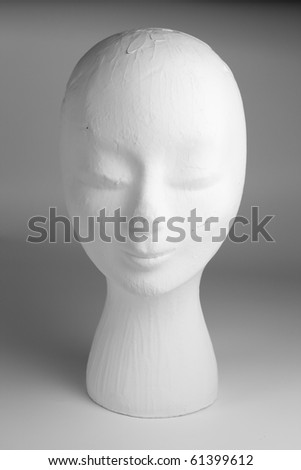 A head of an old mannequin fashion head painted white, worn and used with cracks.