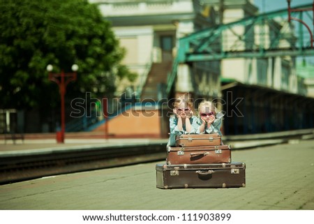 Vintage looking picture of small girls with luggage at the railway station