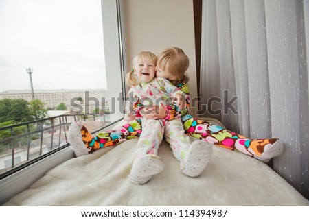Two girls play at the windows-sill in pyjamas before sleep