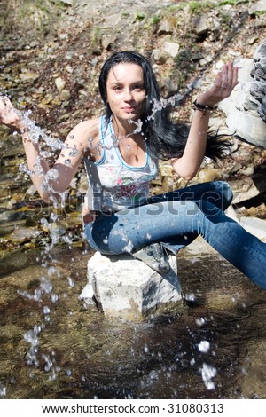 woman plays with water near waterfall
