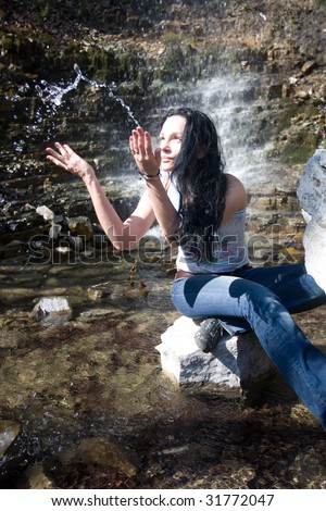 woman plays with water near waterfall