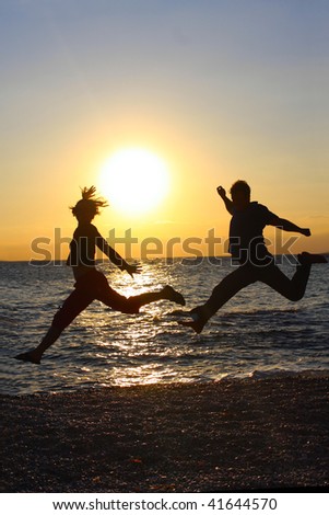 Silhouettes of happy people jumping at sunset