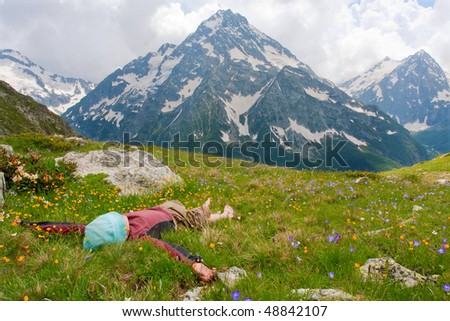 Hiker lies on meadow in mountains