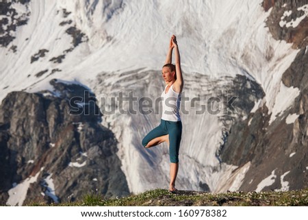 Young woman is practicing yoga in high mountains