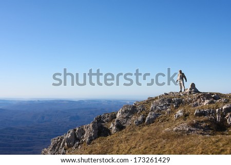 Hiker is standing on top of mountain in Crimea mountains against blue sky