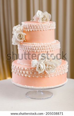 Pink and white wedding cake with individual decoration at withe table
