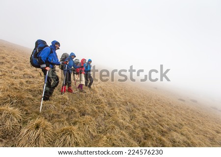 Group of hiker are walking in mountains covered with dense clouds