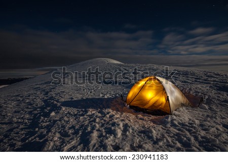 Orange tent in winter forest in night