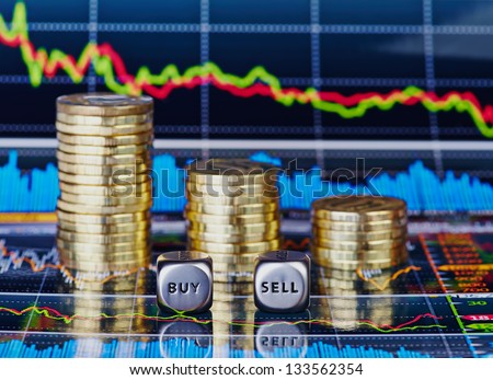 Stacks of coins, dices cubes with the words SELL BUY and down trend chart as the background