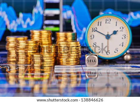 Stacks of golden coins, clock, dices cube with the words SELL. The financial chart as background. Selective focus