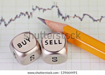 Dices cubes with the words SELL BUY, pencil and financial chart as background. Selective focus.