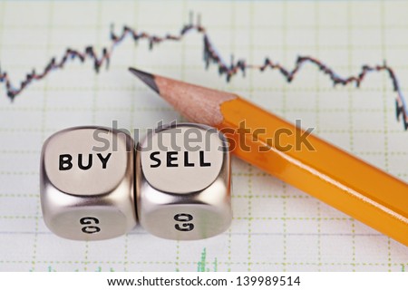 Dices cubes with the words SELL BUY, pencil and financial chart. Selective focus.