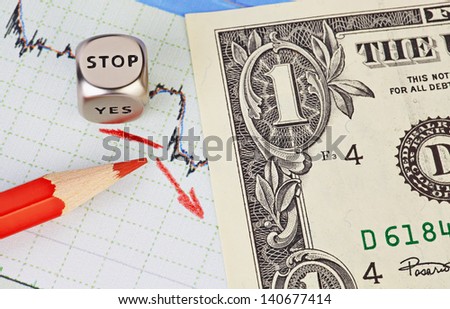 Downtrend financial market chart, red pencil, red arrow, dices cube with the word STOP and one-dollar banknote. Selective focus