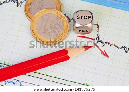Downtrend financial chart, red pencil, red arrow, dices cube with the word STOP and one-euro coins. Selective focus