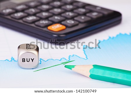 Uptrend financial chart of the stock market, green arrow, calculator, green pencil and dices cube with the word BUY. Selective focus