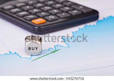 Uptrend financial chart of the stock market, green arrow, calculator and dices cube with the word BUY. Selective focus
