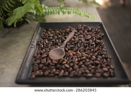 wooden spoon full of coffee beans over surface of instant coffee and beans. Shallow depth of field, focus on spoon beans