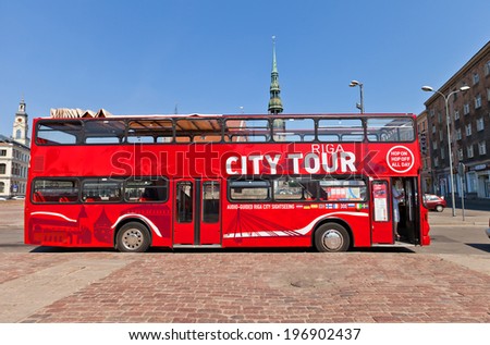 Riga, Latvia - May 25, 2014: Red double-decker city sightseeing bus waiting for tourists on the Latvian Riflemen square in Riga, Latvia