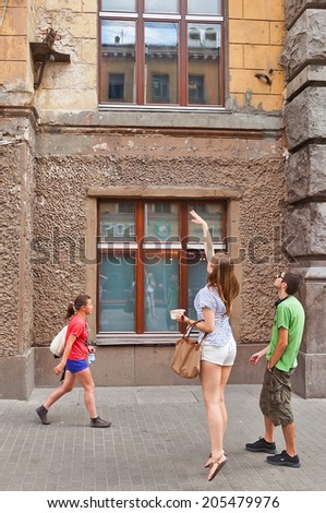 Russia, Saint Petersburg - July 14, 2014: Young woman tries to throw coin to small platform with statue of cat Elisey. According to popular belief success throw will bring a lot of luck