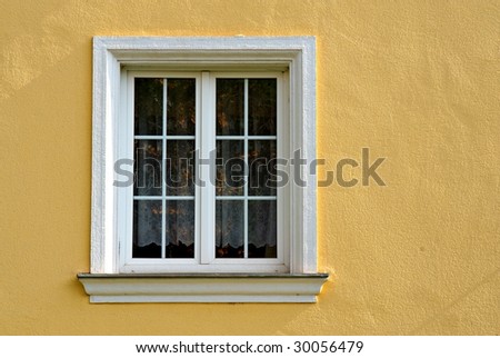 simple window with white frame on yellow facade