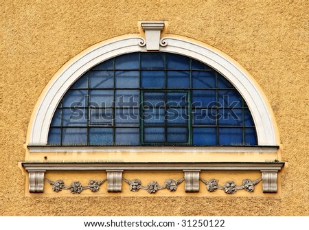 round blue window with bars on light brown facade