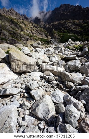 white and dark gray stones, boulders and mountains, vertical with dark blue sky