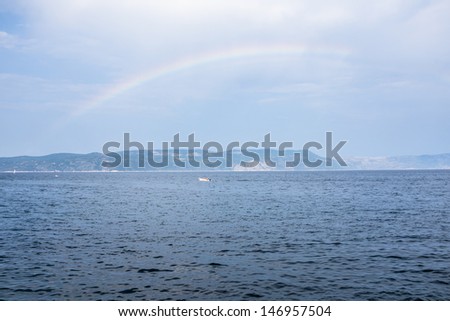 a rainbow over sea with a small boat