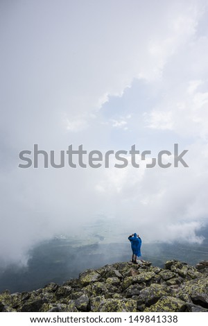 tourist in raincoat in mountains, rain is coming