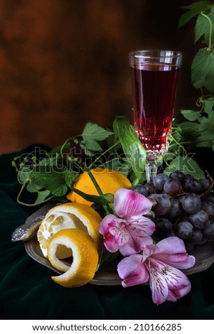 Still life in antique style with a glass of wine, grapes and two lemons