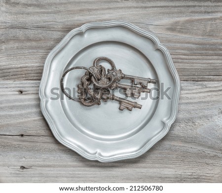 Three old rusty keys on a tin plate