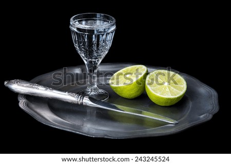 Glass of vodka, sliced lime and old knife on a tin plate