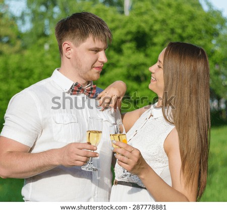 Newlyweds drinking champagne outdoors at summer day