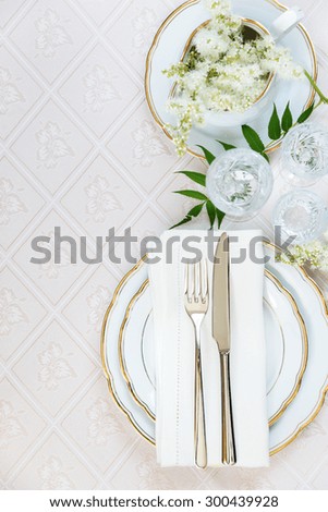 Top view of the beautifully decorated table with white plates, crystal glasses, linen napkin, cutlery and white flower on luxurious tablecloths, top view, with space for text