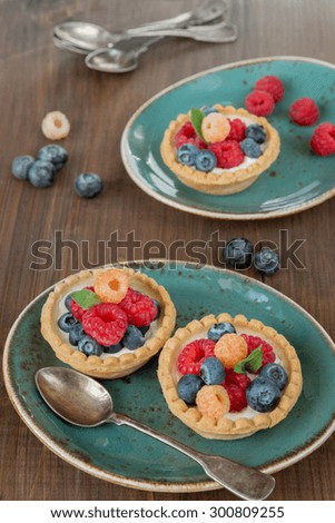 Fruit tartlets with raspberries and blueberries on a blue vintage plates