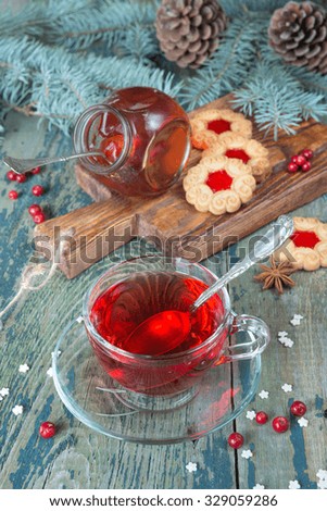 Hot tea in a transparent cup, jam and cookies on a background of Christmas decorations