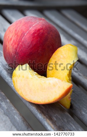 Peach with its slices on a wooden table